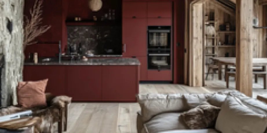 Dark red kitchen with a marble splashback and a linen sofa