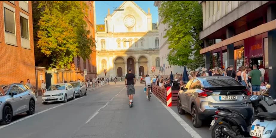 Munich street at golden hour with a church facade and a pavement cafe