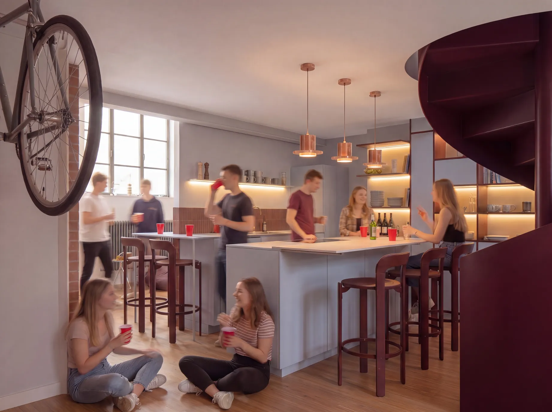 Kitchen of the Milan loft: light blue built-in carpentry, copper pendants and the red spiral stair